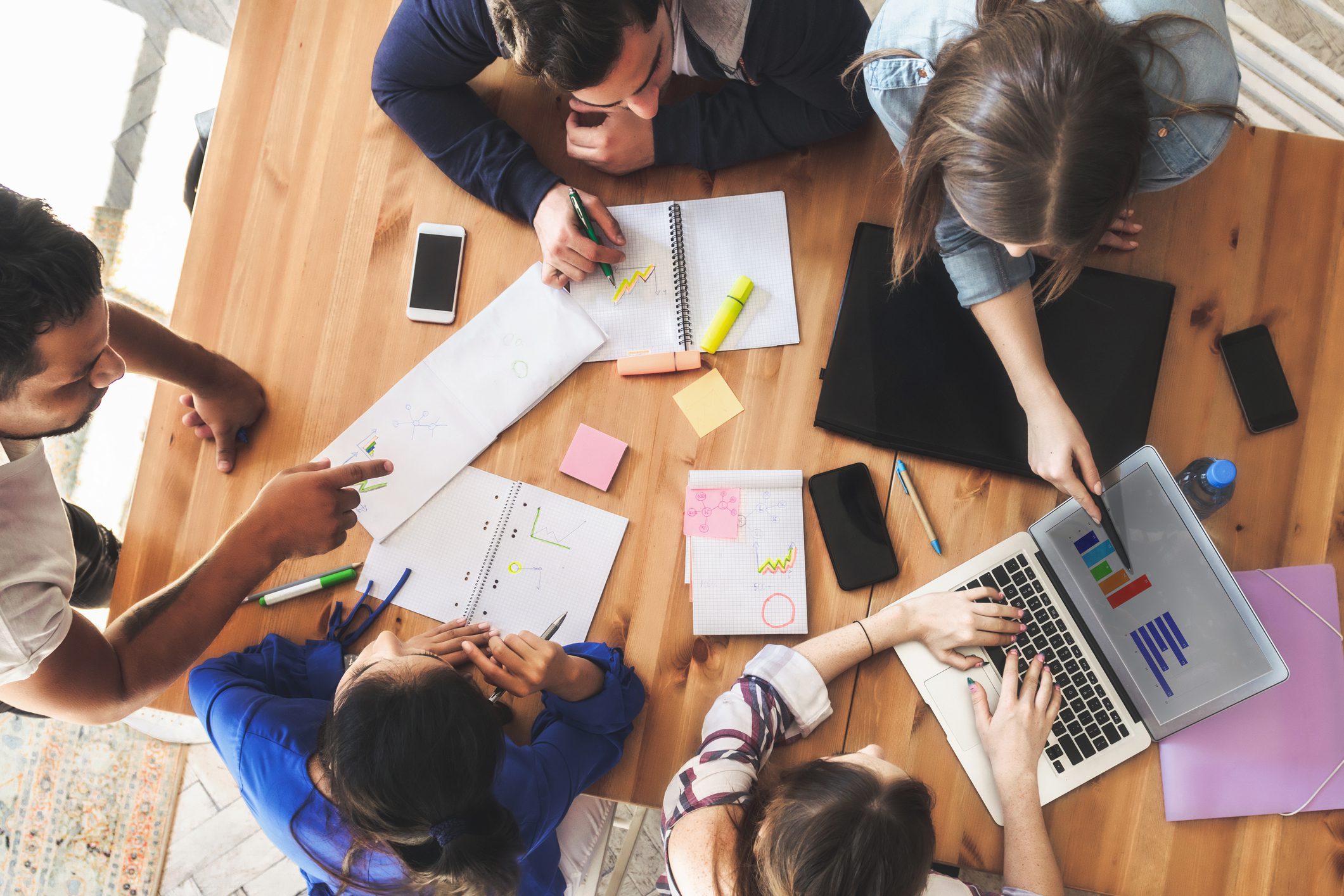 overhead view on young business people around wooden desk