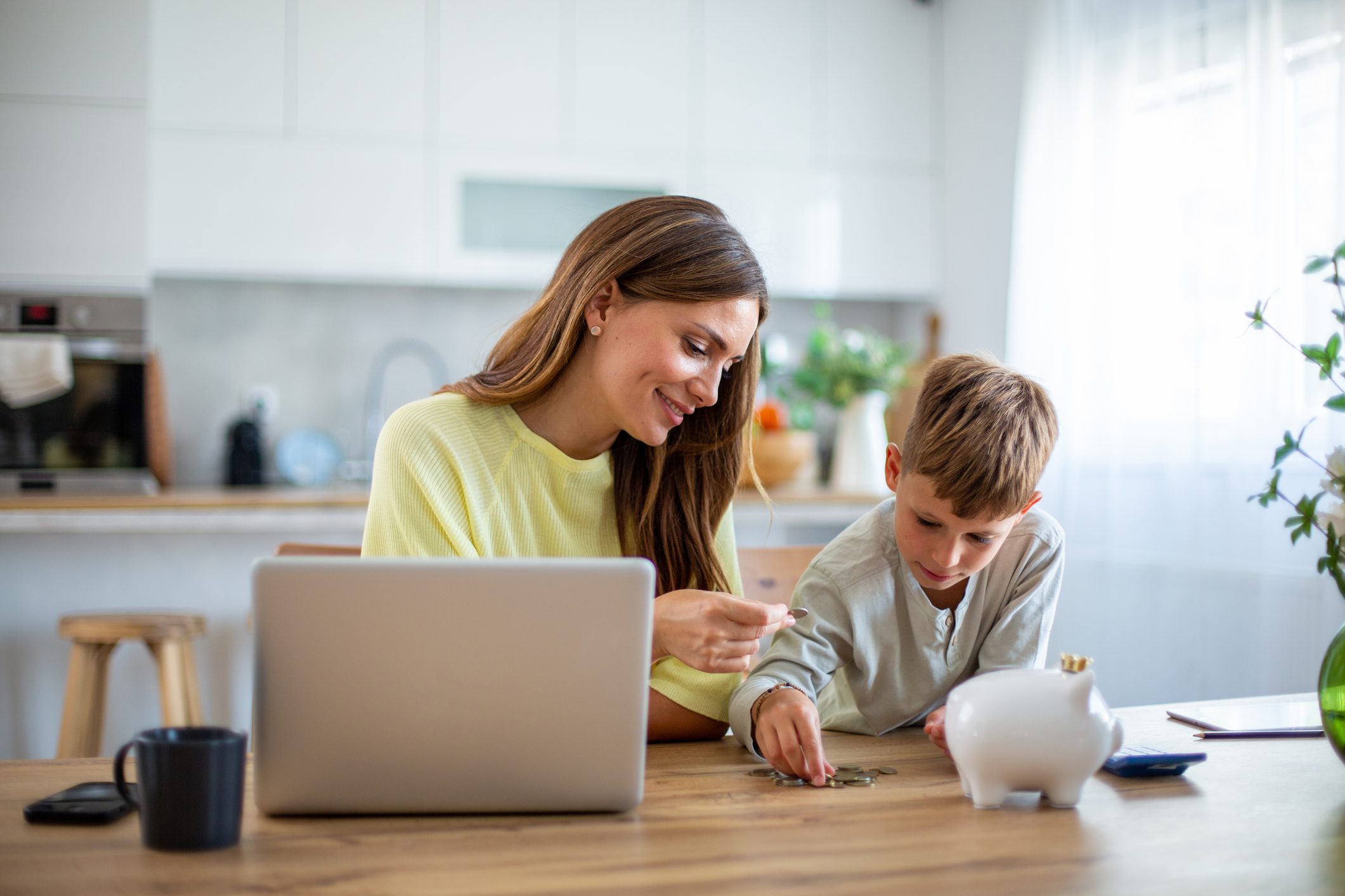 Mother and son learning about personal finance and counting coins at home